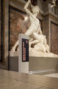 A sign showing the way to the exhibition Beethoven Moves. Installed in front of the sculpture "Theseus Fighting the Centaur" by Antonio Canova on the grand stairway of the Kunsthistorisches Museum Vienna.